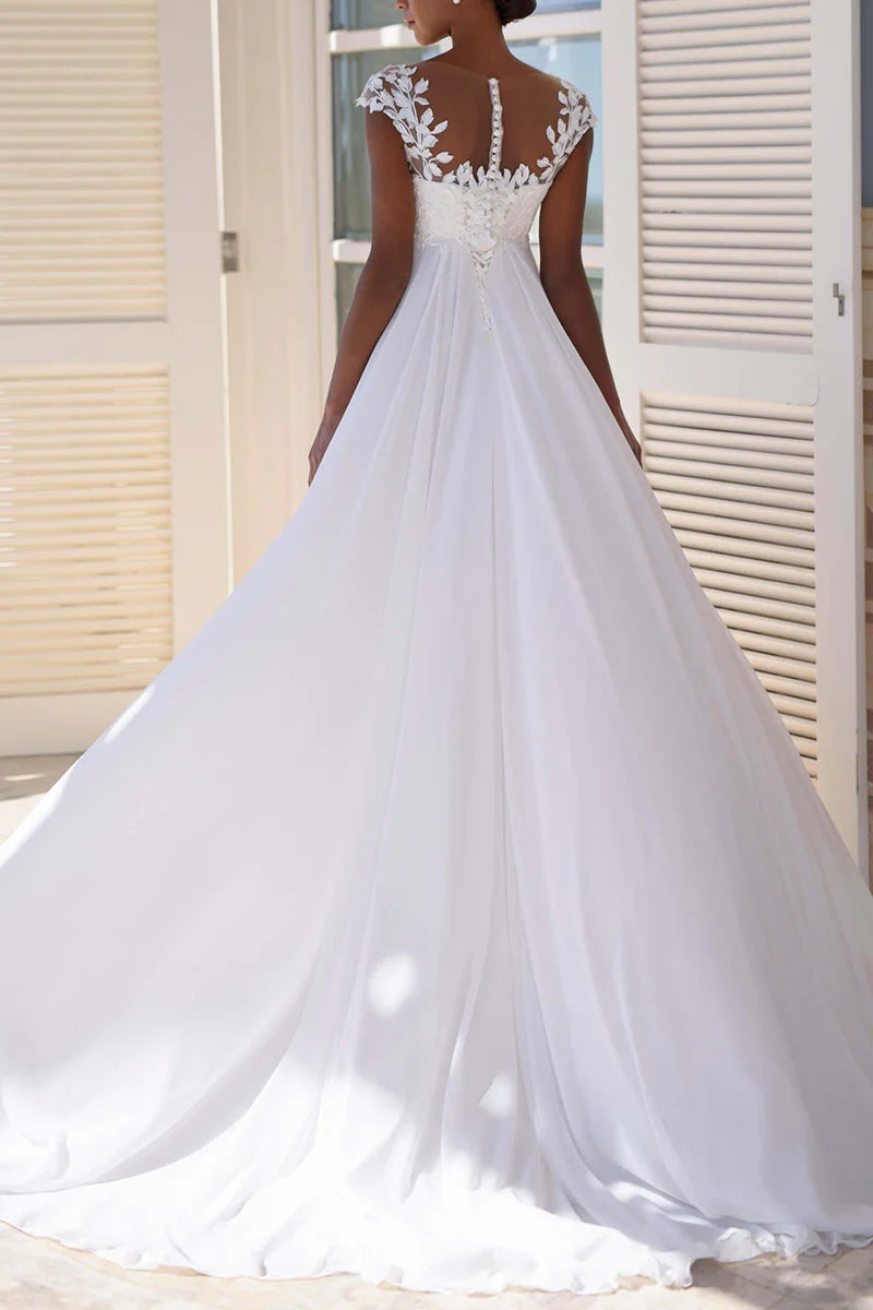 Back view of an A-line wedding dress with lace details and short sleeves, worn by a model.