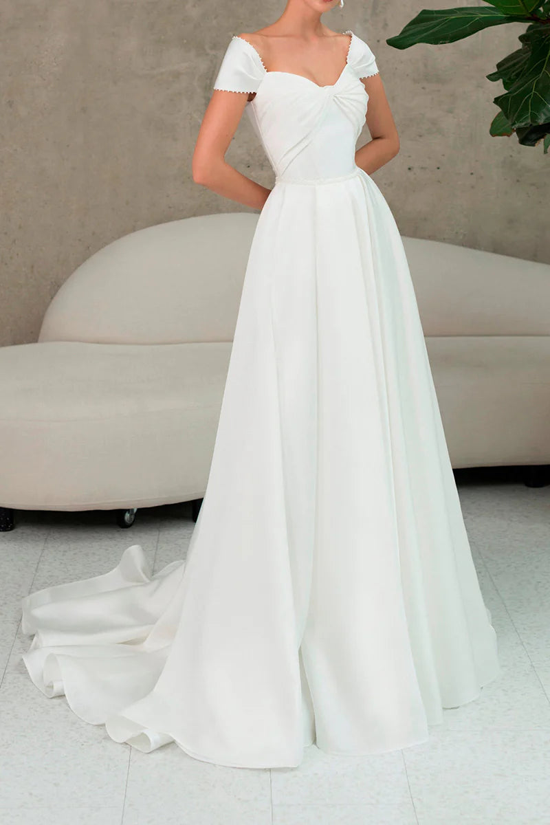 Model wearing an A-line beach wedding dress with a sweetheart neckline and a high slit, standing outdoors.