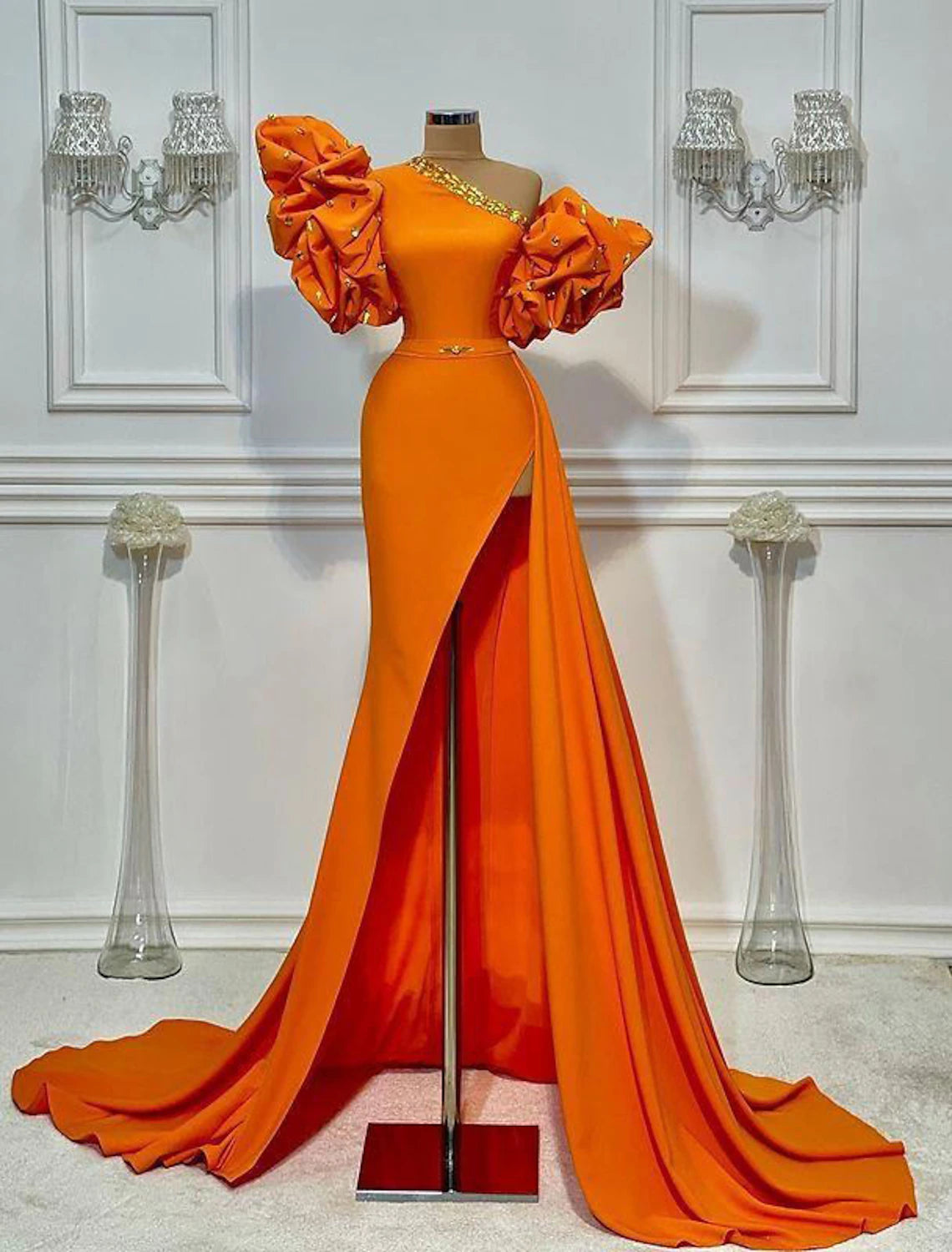 Full view of a woman wearing a luxurious A-line one-shoulder satin evening gown with floral details and a high slit.