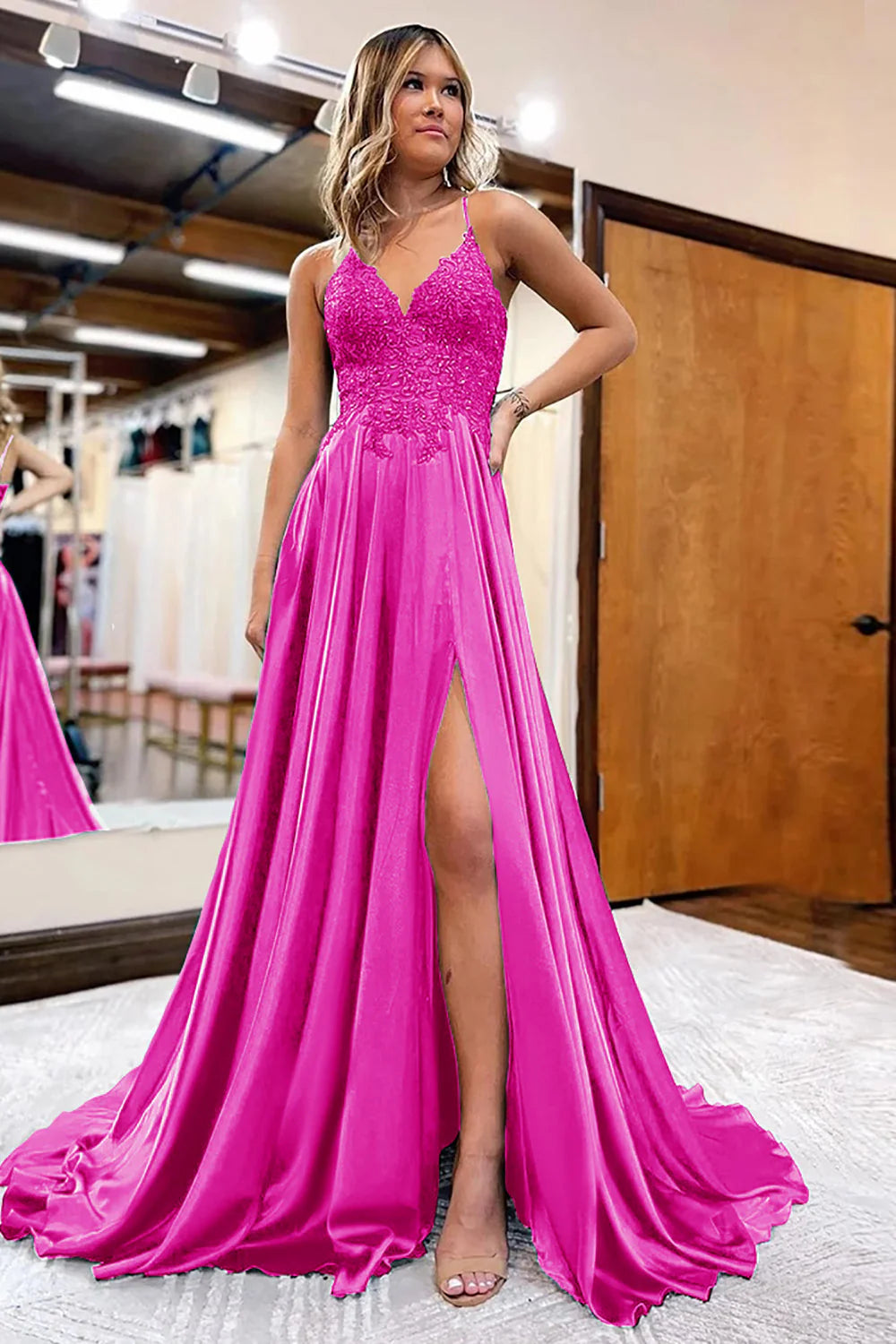 Woman posing in an A-Line satin prom dress with appliques and a high slit, front view.