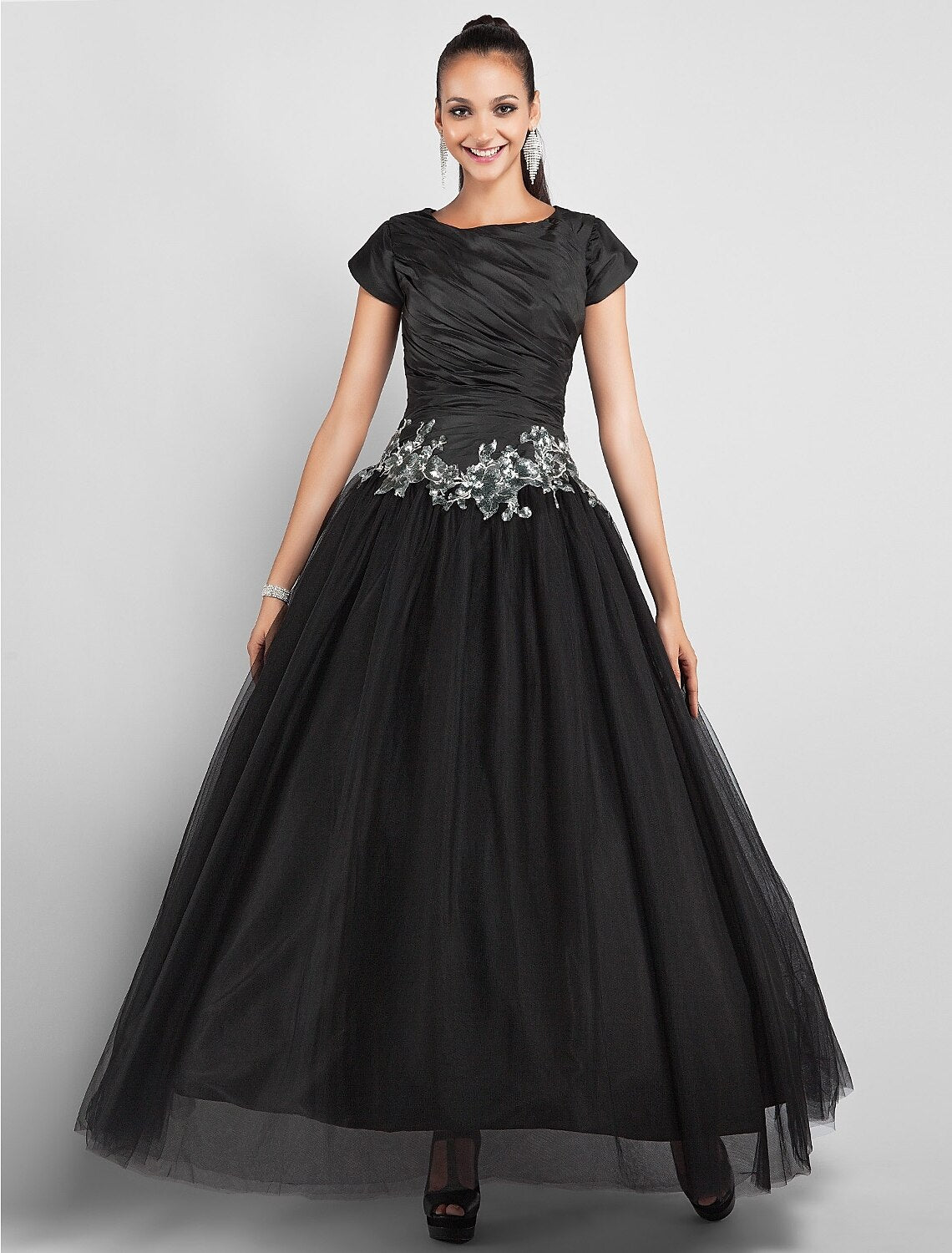 Black taffeta ball gown with jewel neck and short sleeves, featuring appliques and side draping.