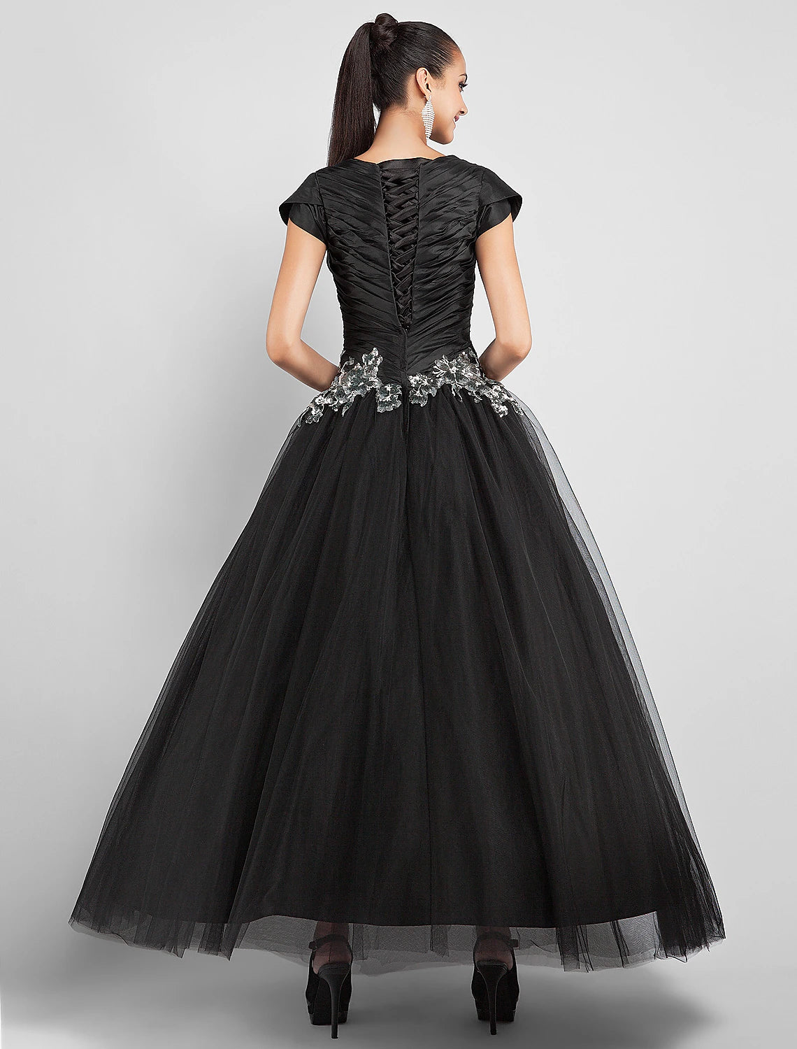 Side view of a black taffeta ball gown, showcasing appliques and elegant side draping.