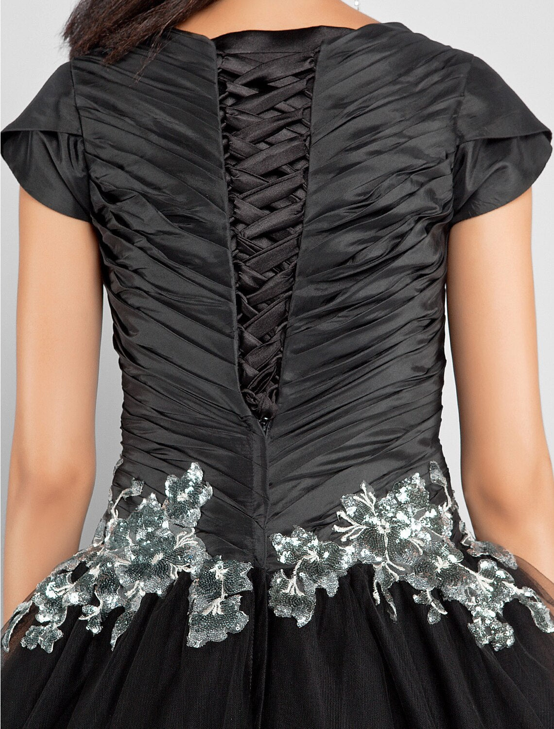 Close-up of the jewel neck and short sleeves on a black taffeta formal dress.