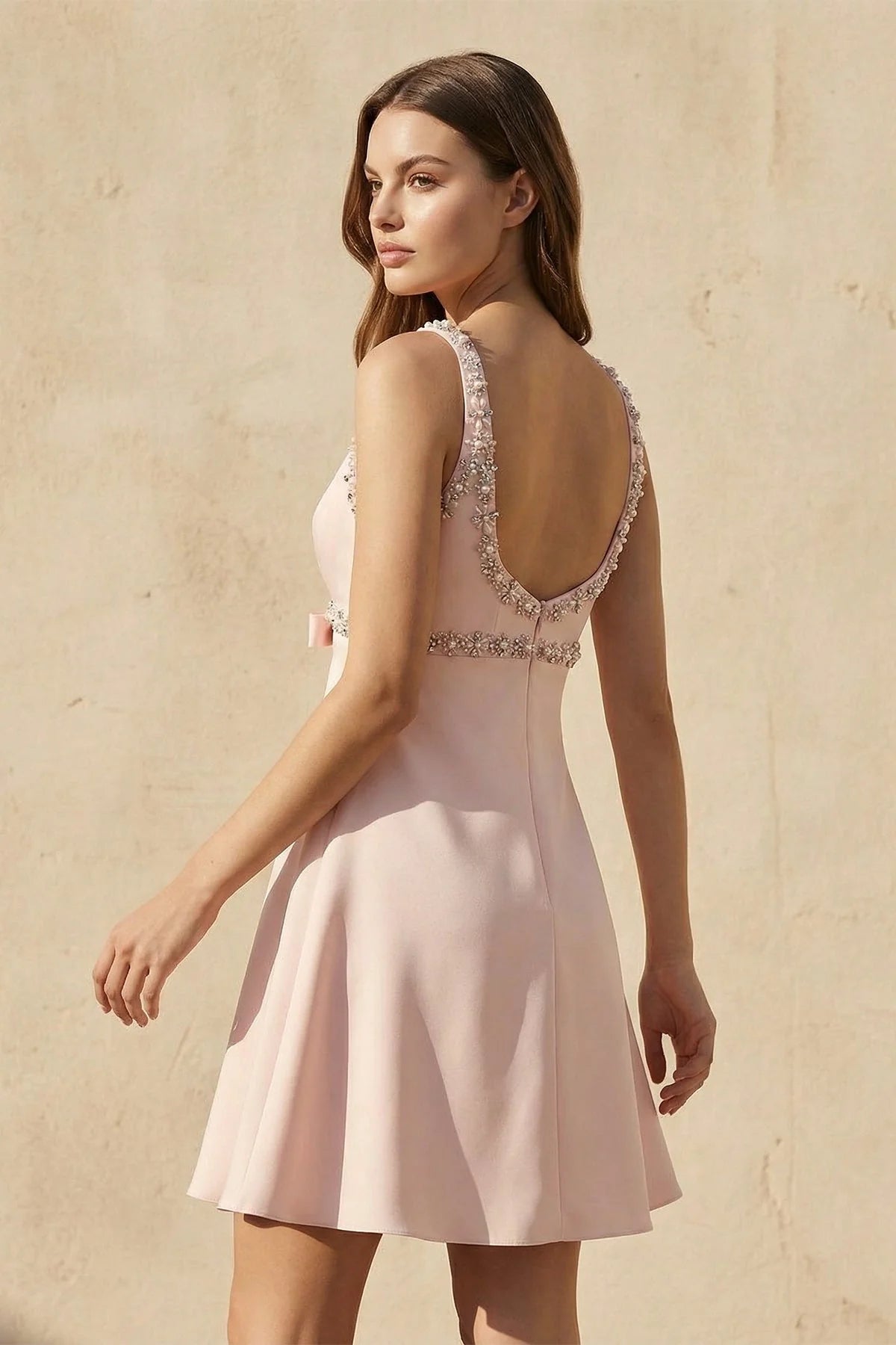 Side view of blush pink A-line mini homecoming dress with V-neck and beaded straps.