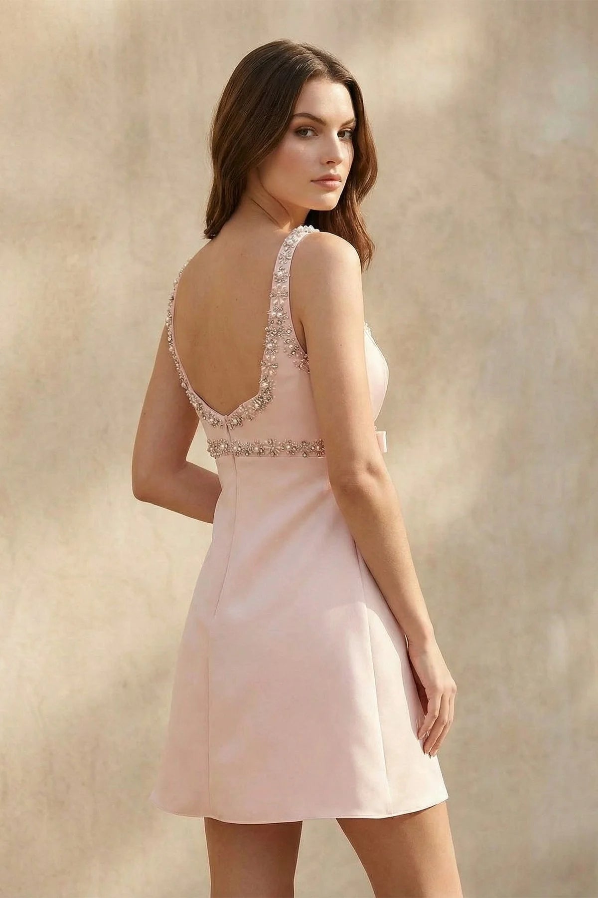 Model wearing the blush pink V-neck A-line mini homecoming dress, showcasing its flow.