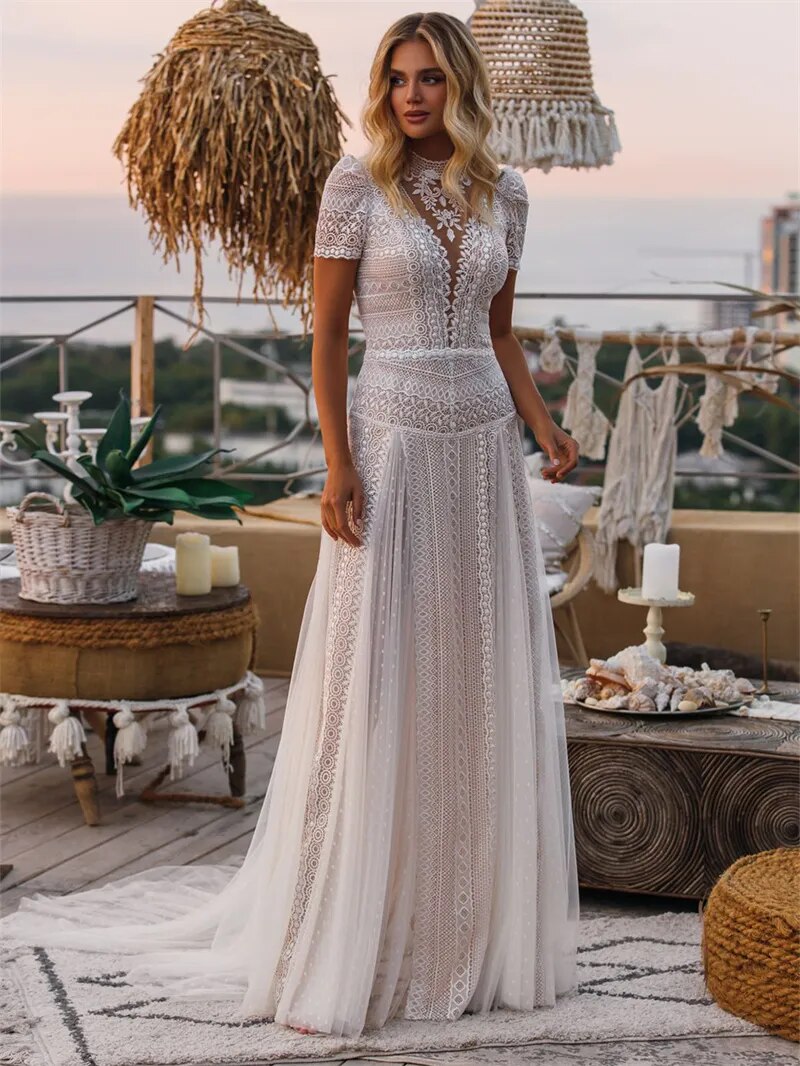 Bohemian A-line wedding dress with illusion neckline and short lace sleeves, front view.