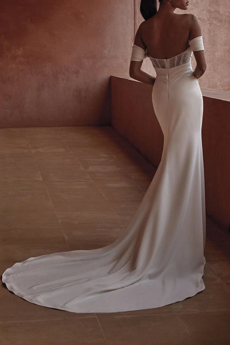 Full view of a white off-shoulder bridal gown with a flowing A-line skirt.