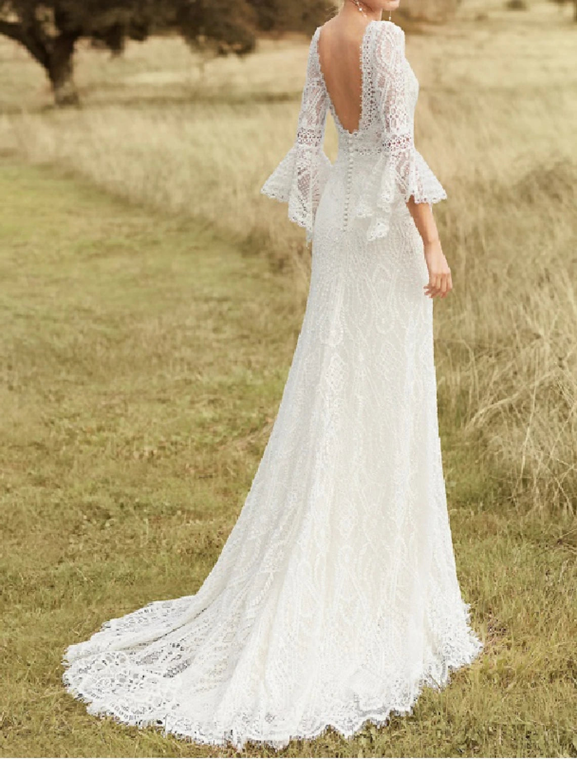 Bride in a romantic A-line wedding dress with scoop neck and long sleeves outdoors.