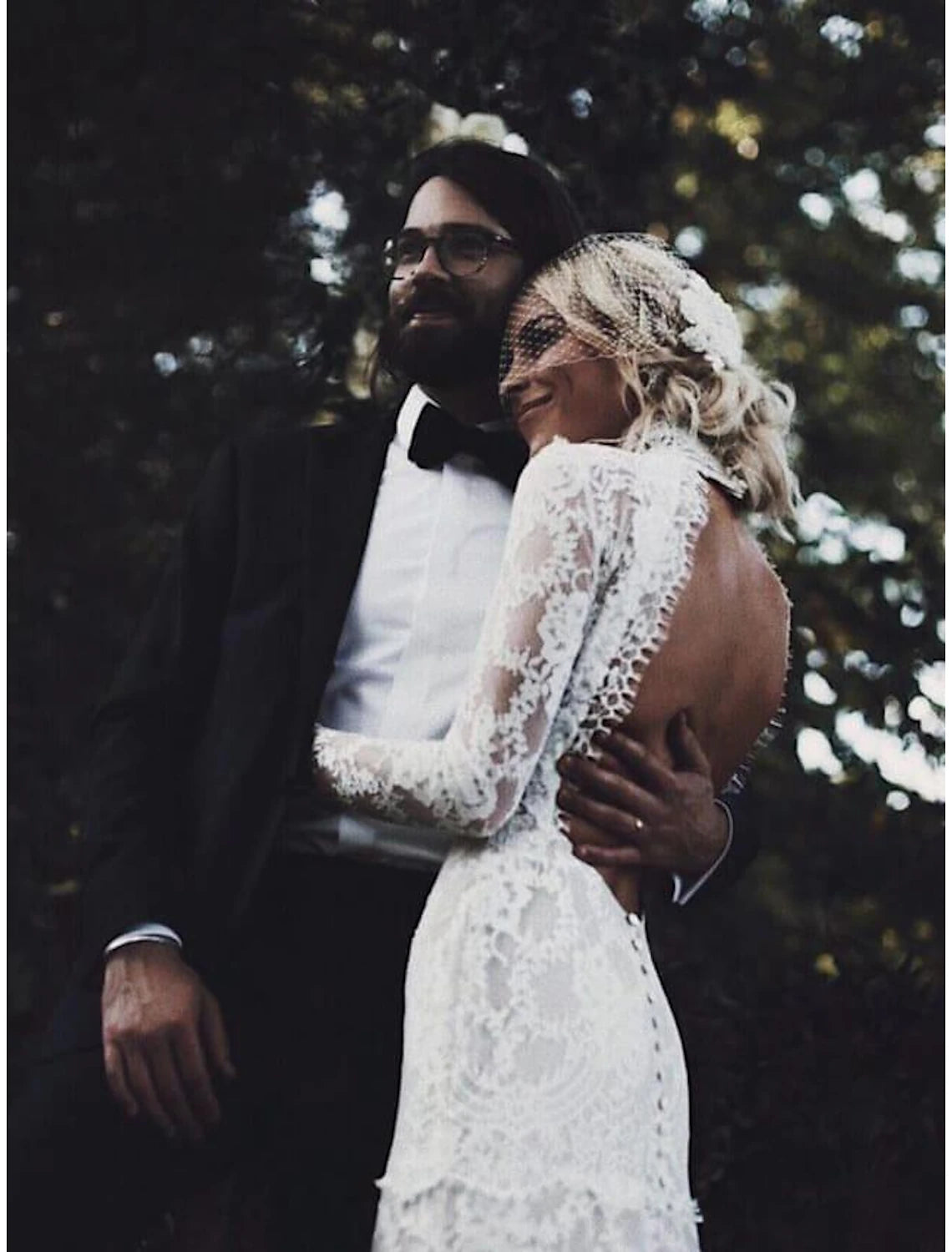 Side view of a bride in a white lace wedding gown with a court train.