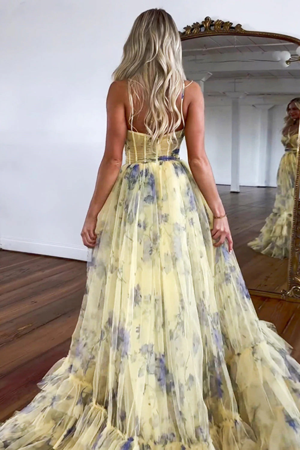 Back view of a yellow A-line formal dress with ruffled tulle skirt.