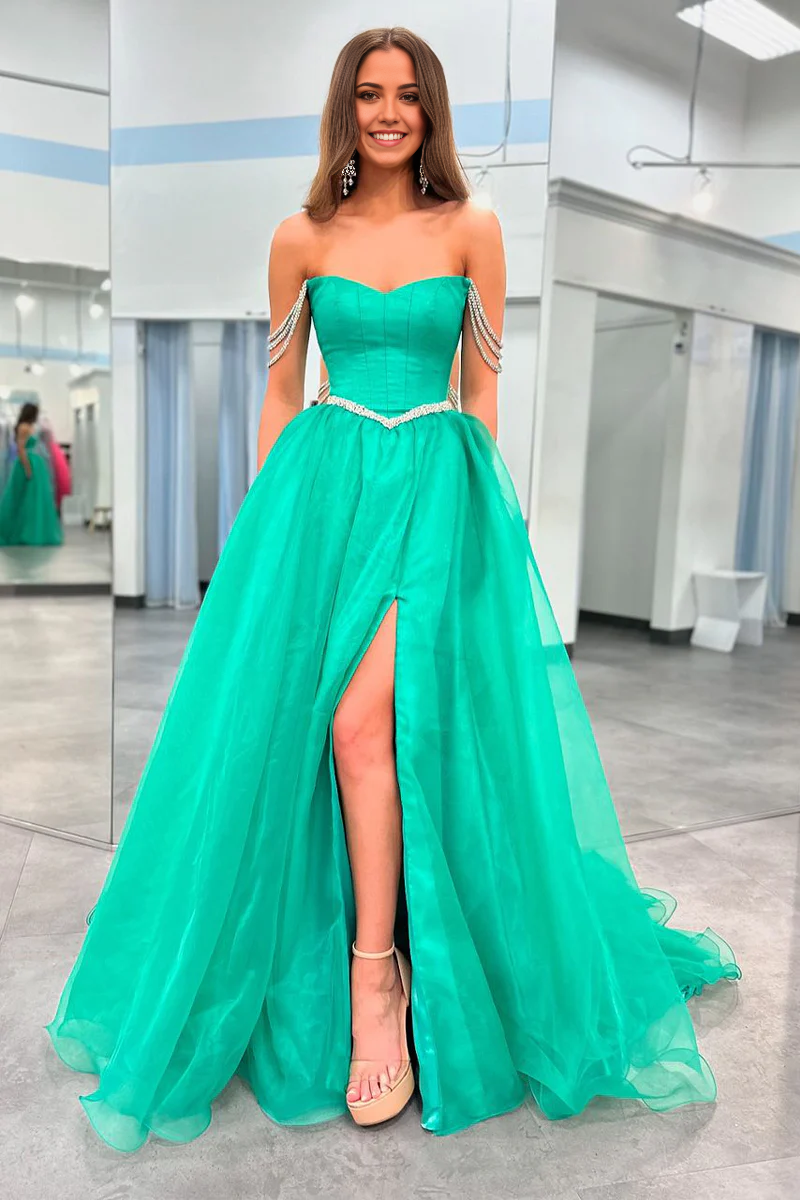 Model wearing a green A-line strapless prom dress with delicate beaded straps.