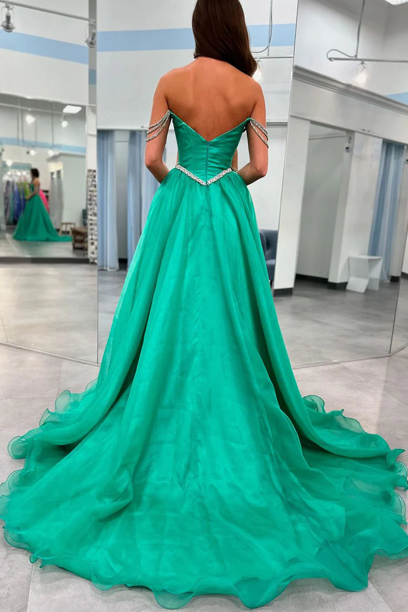 Back view of a model in a long green A-line evening gown with elegant beaded straps.