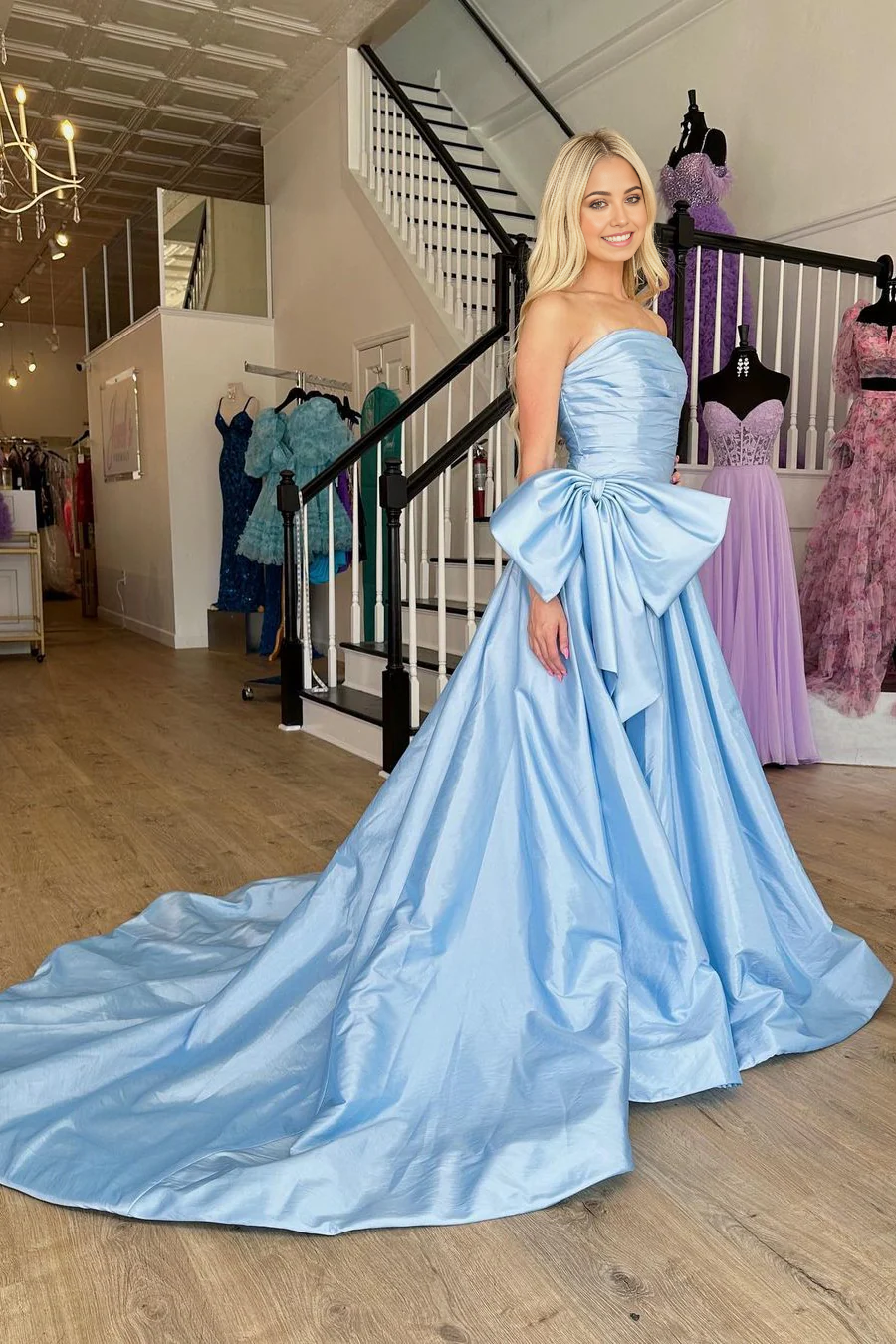 Full length view of a model wearing a light blue strapless A-line prom dress.