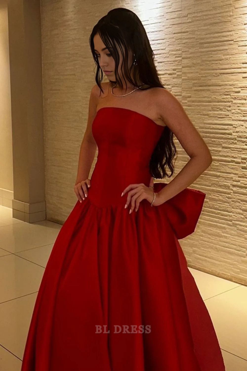 Model wearing a red A-line strapless long formal dress with a bowknot detail.