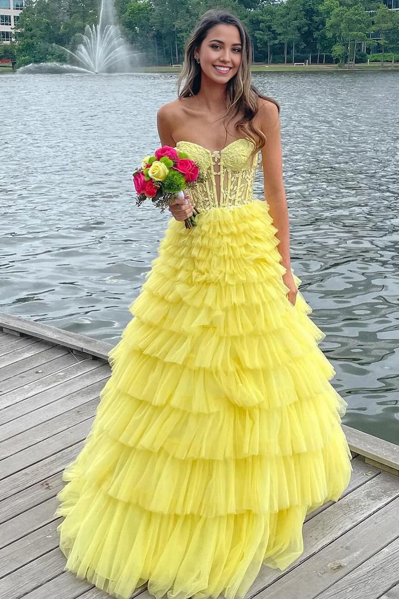 Yellow A-line strapless prom dress with ruffle tiers and flowing tulle skirt.