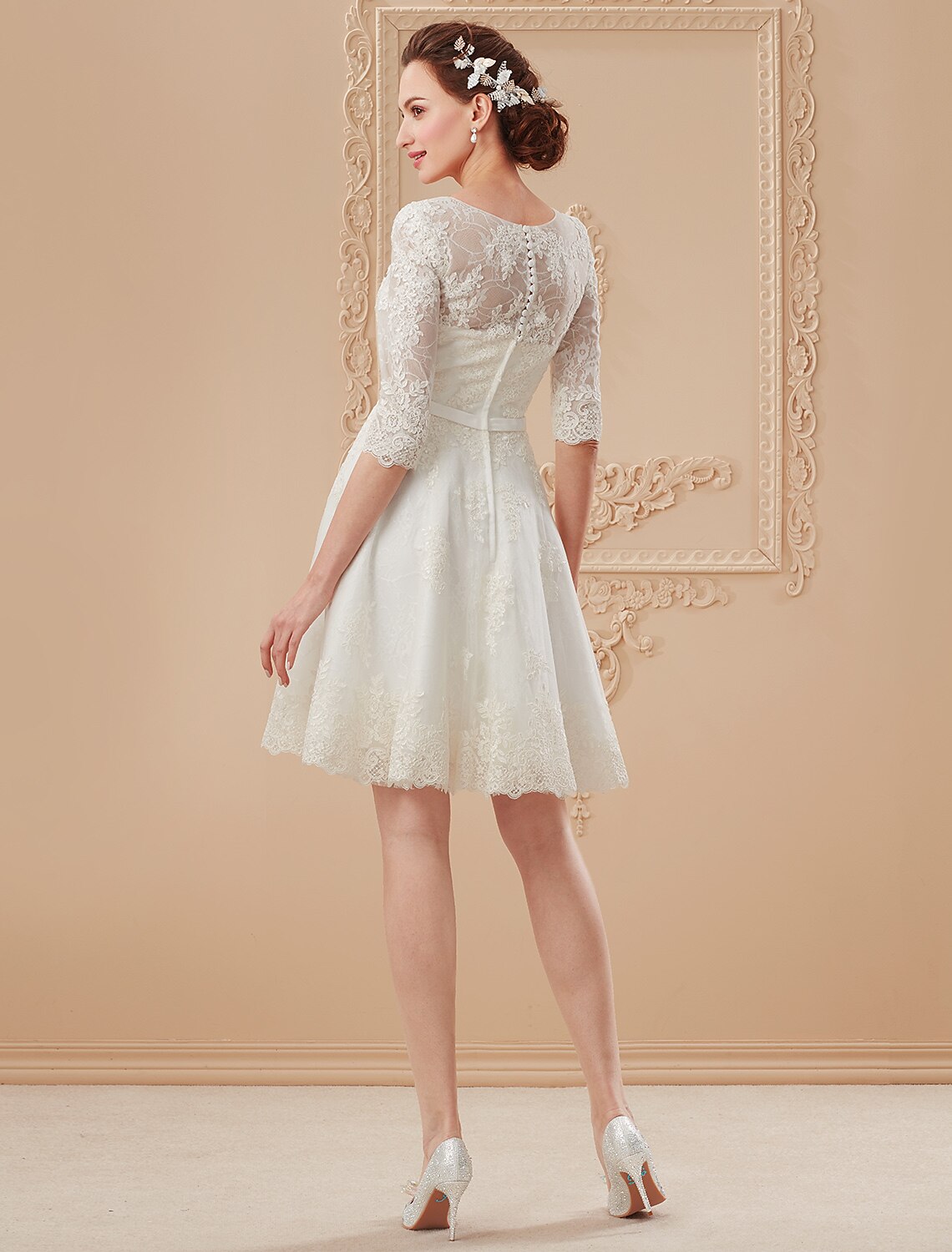 Back view of a white knee-length lace wedding dress with a ribbon detail.
