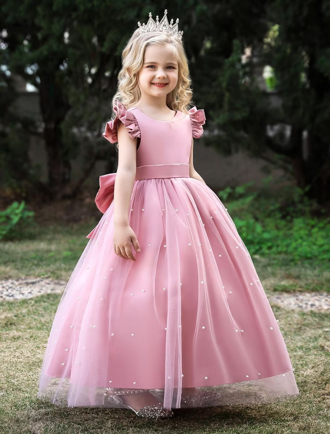Young girl wearing a gold sleeveless princess tulle maxi dress with a bow.
