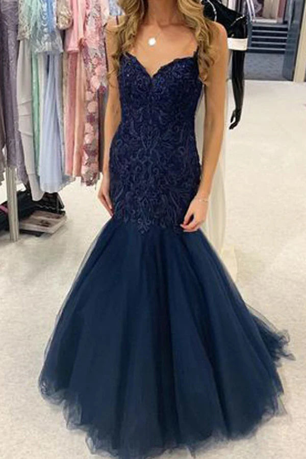 Woman wearing a navy blue mermaid sweetheart long prom dress with lace details.