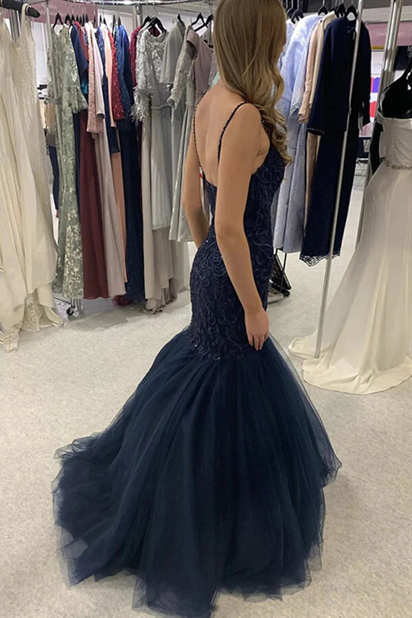 Woman posing in a navy blue mermaid sweetheart lace evening gown.