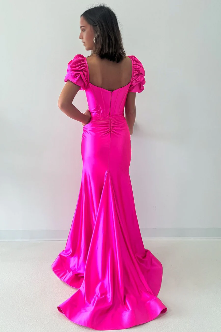 Back view of a model in a hot pink mermaid V-neck satin long formal dress.
