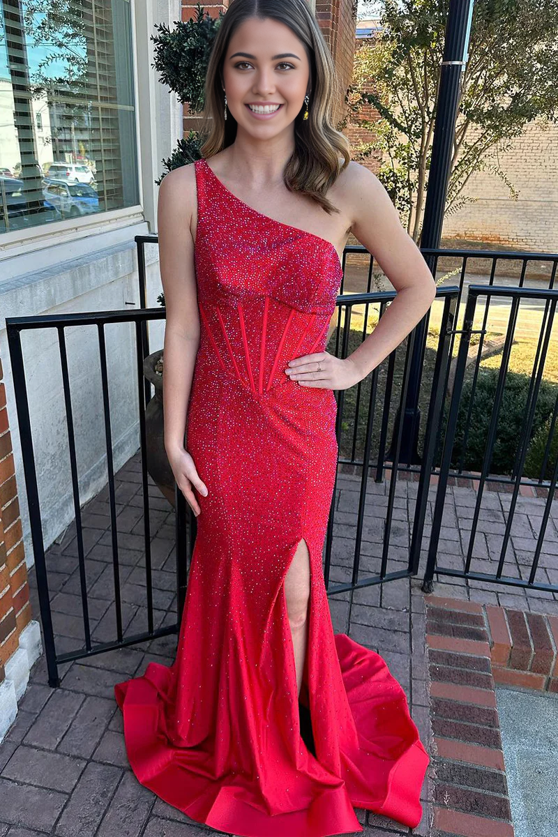 Model wearing a red one-shoulder mermaid prom dress with beading and a high slit.