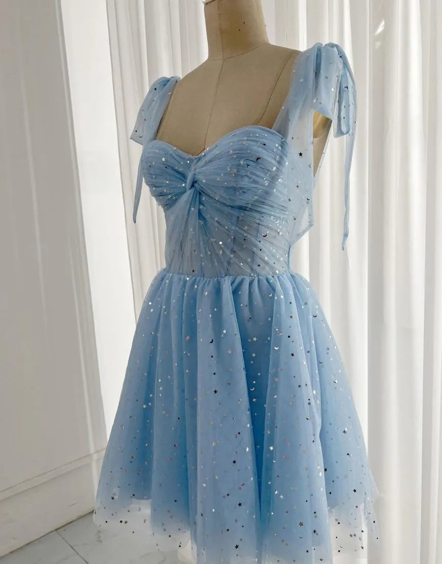 Model wearing a charming short A-line homecoming dress with tie straps and a corset back.