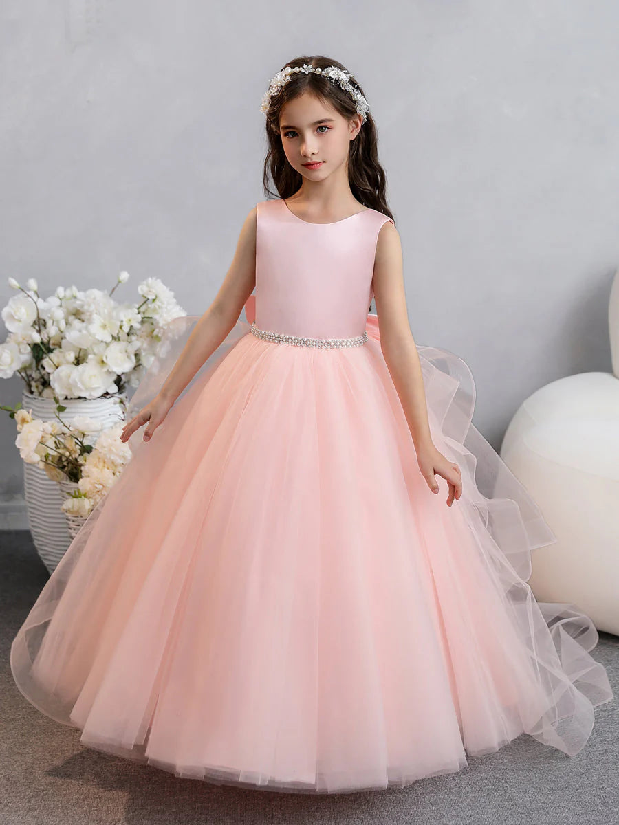Flower girl in an elegant white tulle ball gown with ruffles, pearls, and a bowknot.