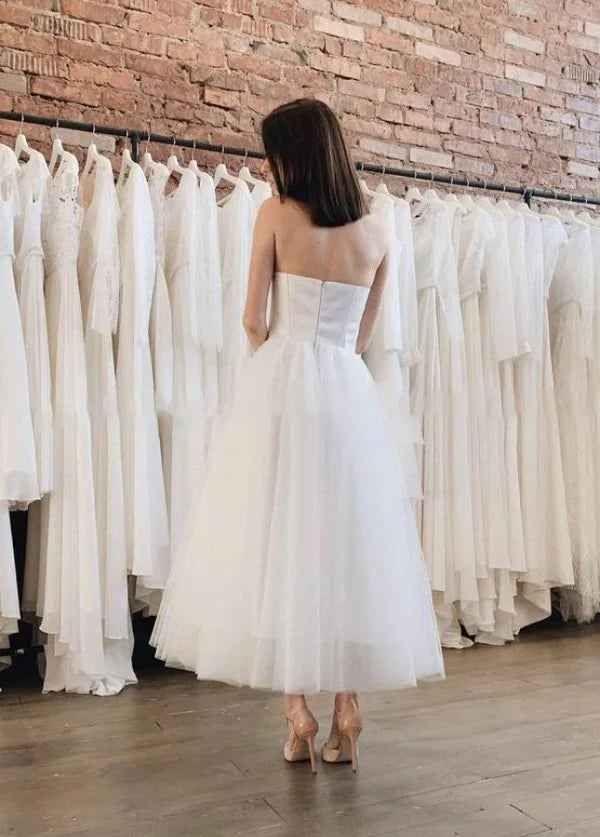 Side view of an A-line backless strapless tea-length tulle wedding dress.