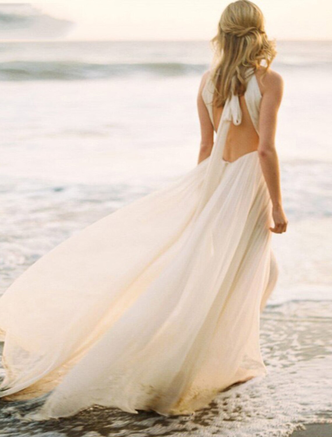 Close-up of the open back and halter neckline of a white chiffon wedding dress.