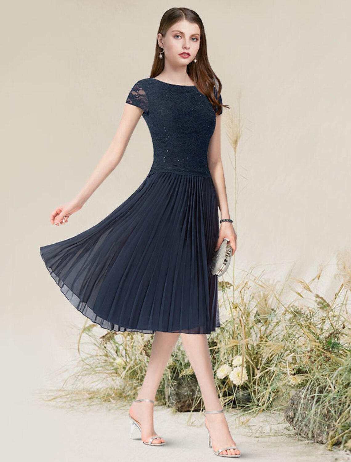 Woman wearing an elegant A-line short sleeve jewel neck chiffon dress with pleats.