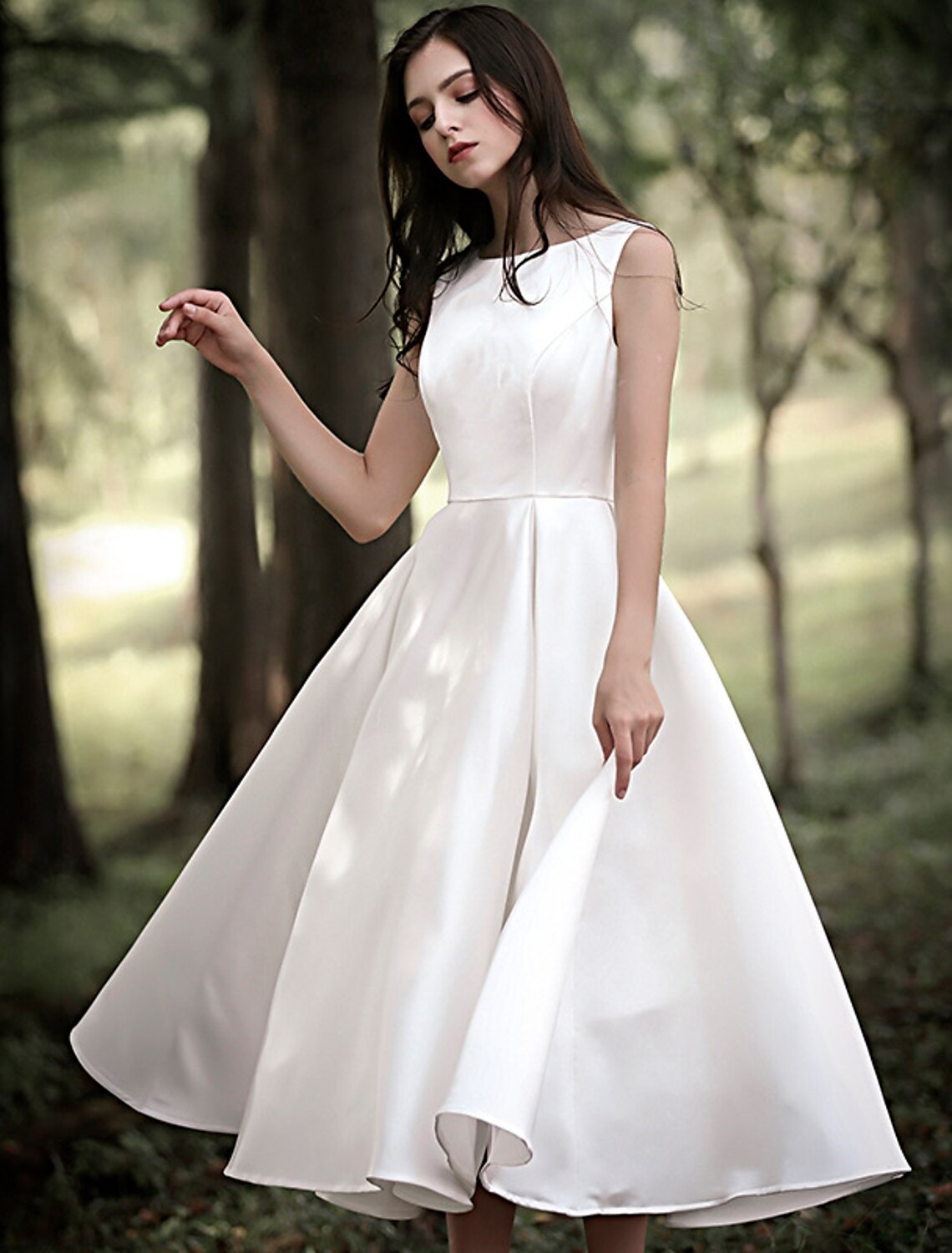 Full length view of a white A-line tea length satin dress for wedding receptions.