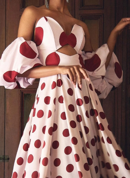 Back view of a woman in a flowy A-line halter V-neck polka dot maxi dress.
