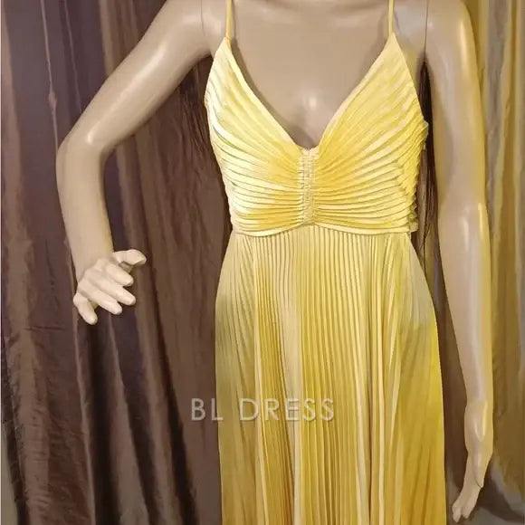Close-up of the pleated detail on a yellow formal dress.