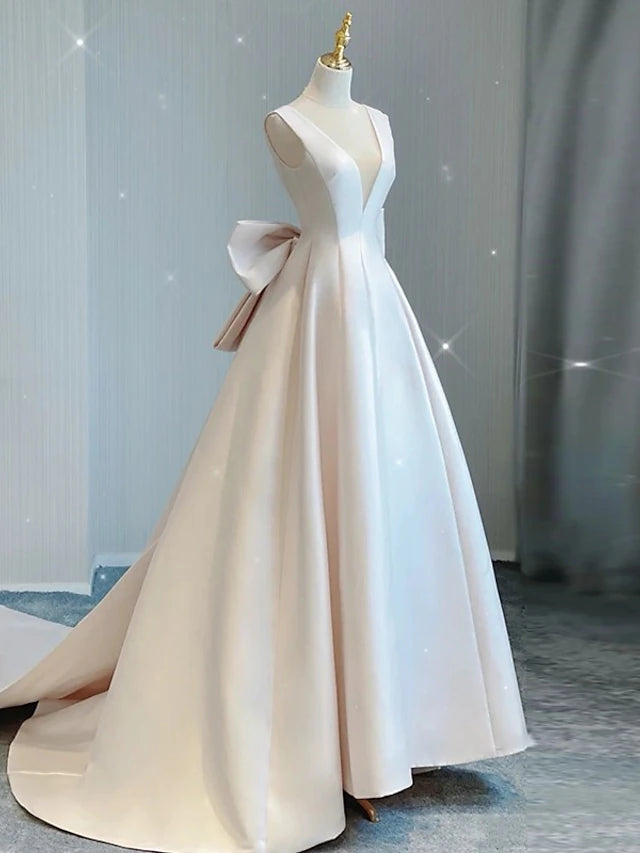 Close-up of the V-neckline and bow detail on the satin wedding dress.