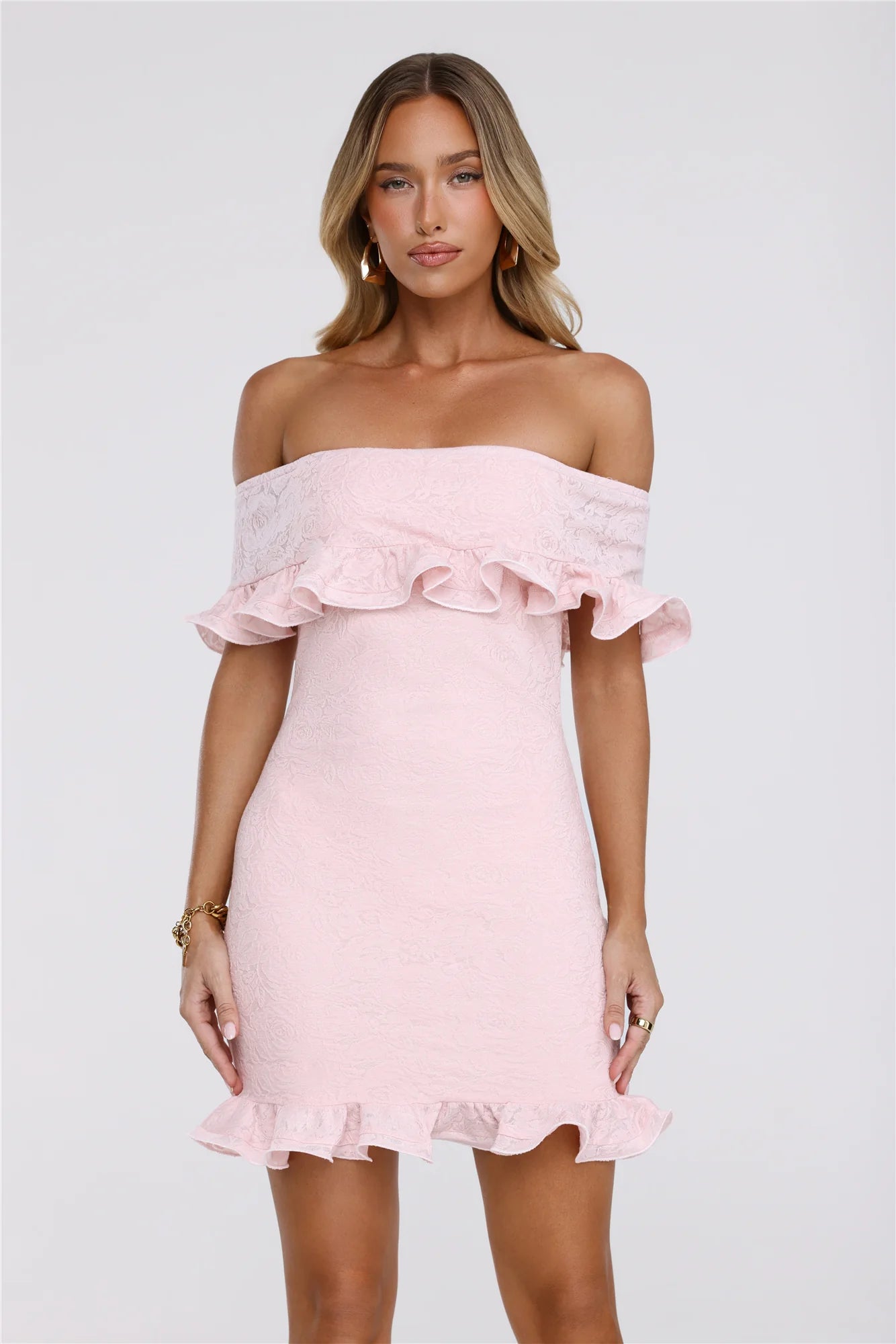 Model wearing a pink lace off-shoulder mini dress with ruffle trim, front view.