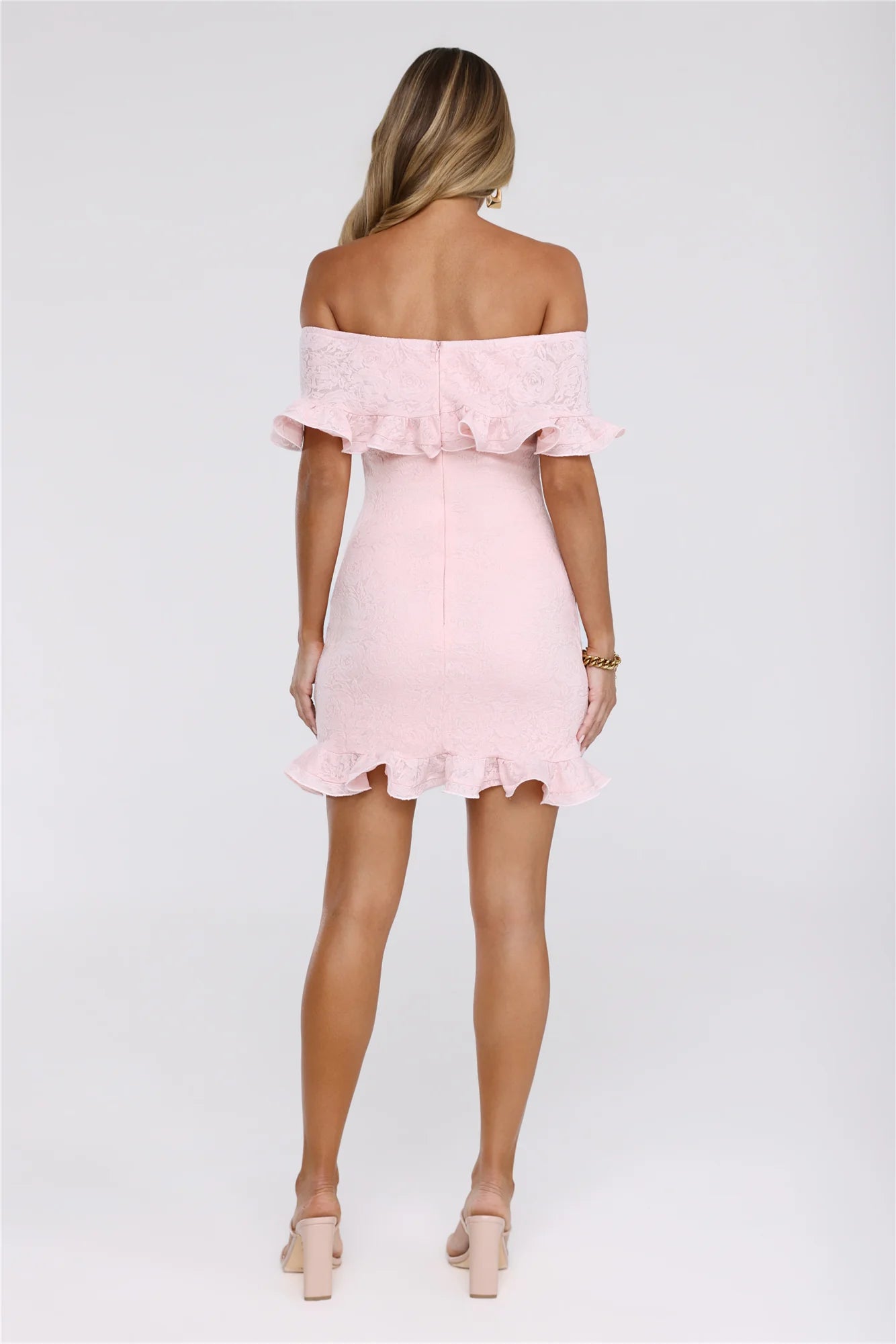 Side view of the fitted pink lace off-shoulder mini dress, highlighting the ruffles.