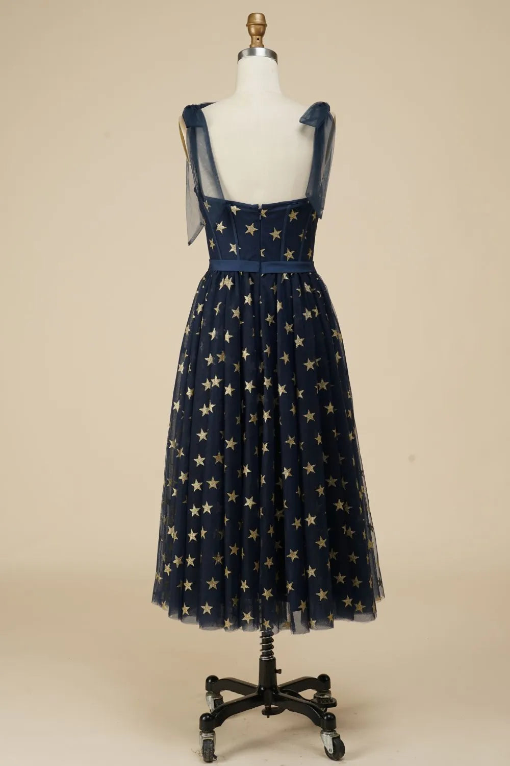 Back view of navy A-line tea length dress with star pattern.