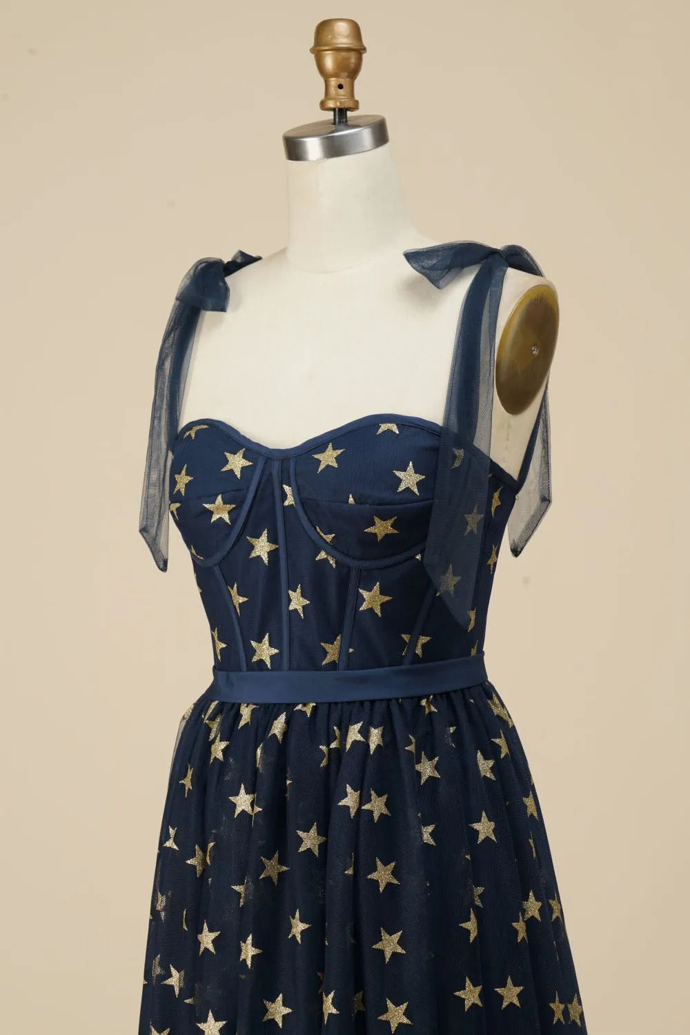 Side profile of navy A-line tea length dress with star pattern.