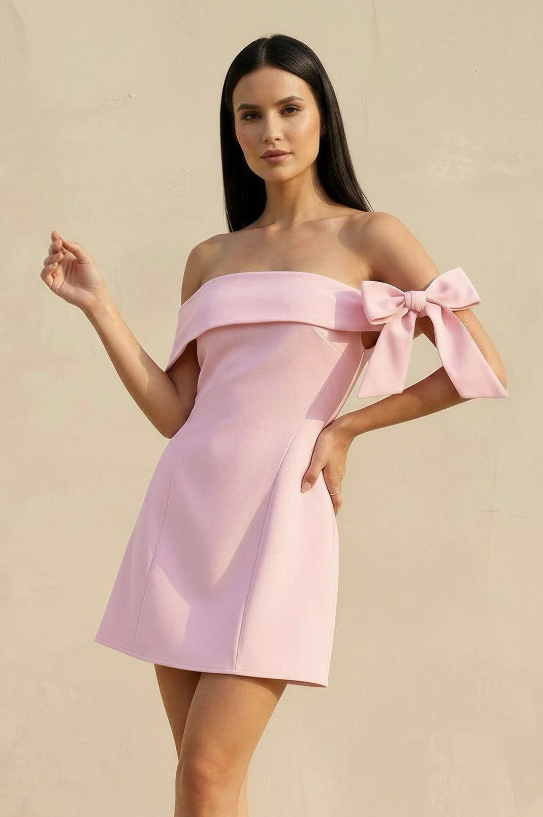 Woman wearing a chic off-shoulder bodycon mini homecoming dress with a large bow detail.