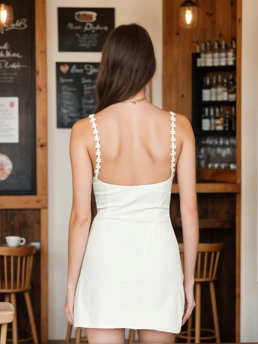 Side view of a woman in a sheath column mini dress, highlighting the floral strap detail.