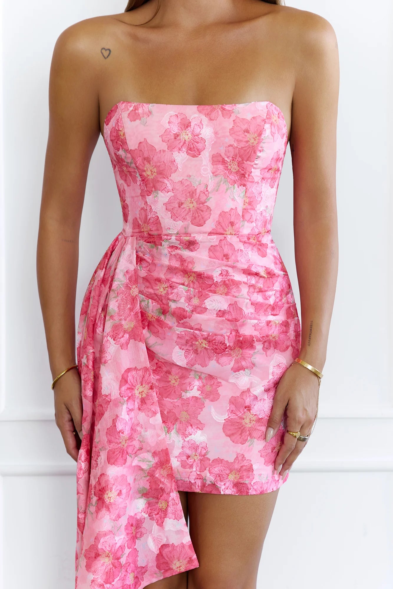 Model posing in a pink floral strapless mini dress, showing the full design.