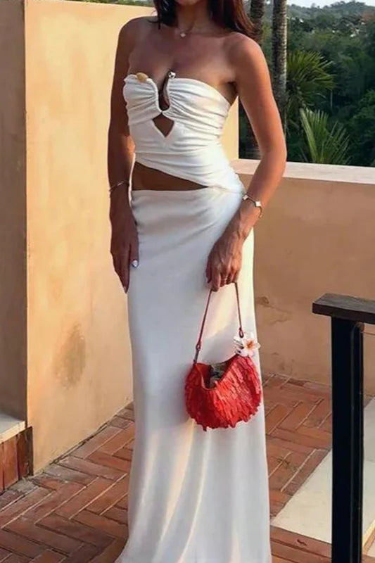 Woman wearing a white strapless cutout maxi prom dress.