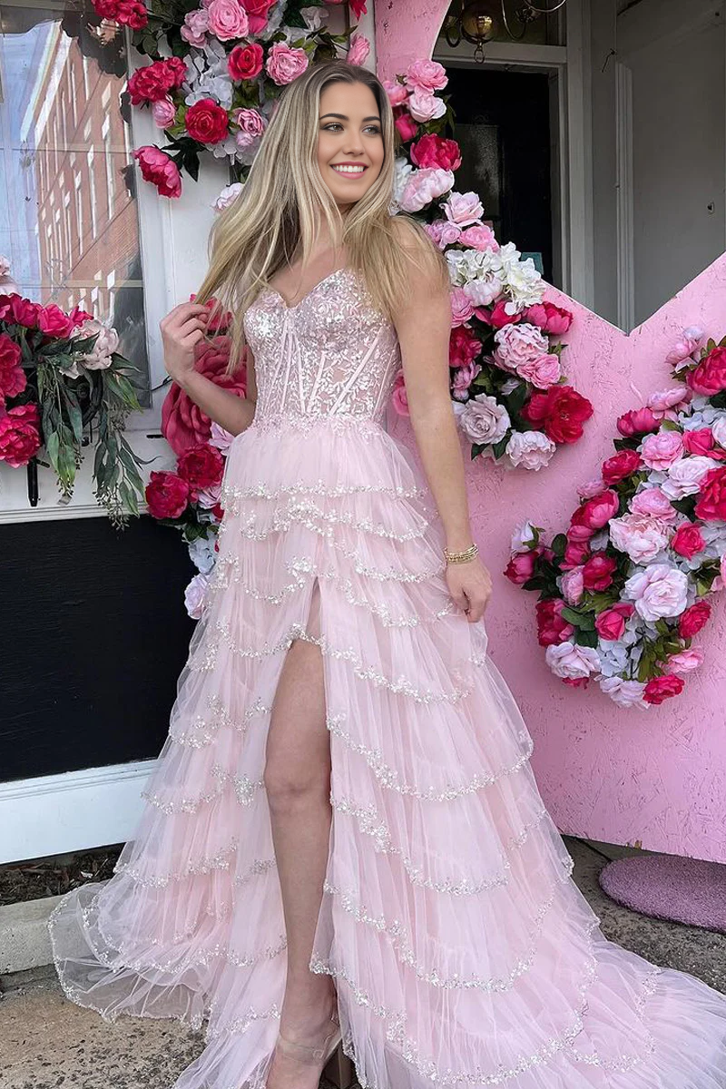 Model wearing a light pink A-line tulle prom dress with a sweetheart neckline and a high slit.