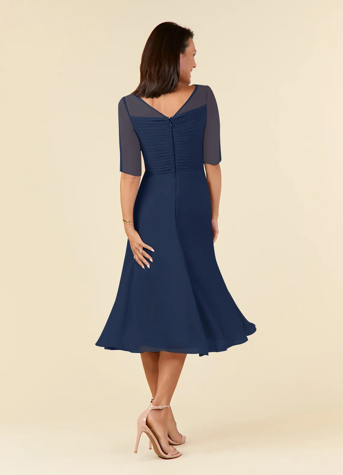 Side view of a woman in a dark navy A-line pleated chiffon dress.