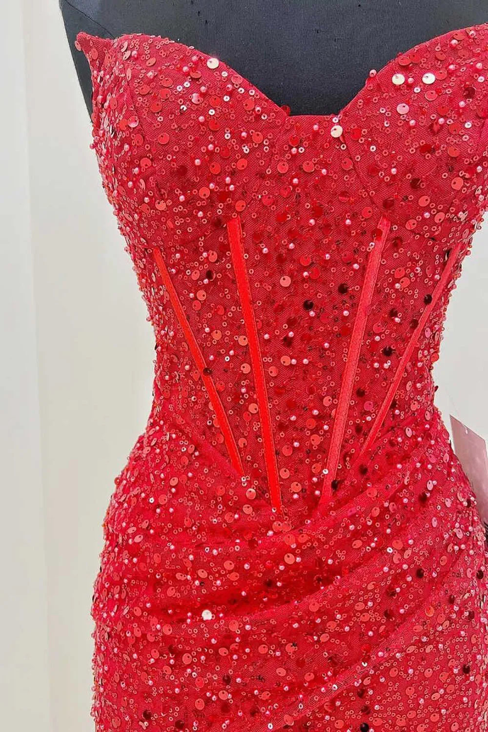 Woman posing in a manycolor sequin dress, showing the full length and sparkling fabric.
