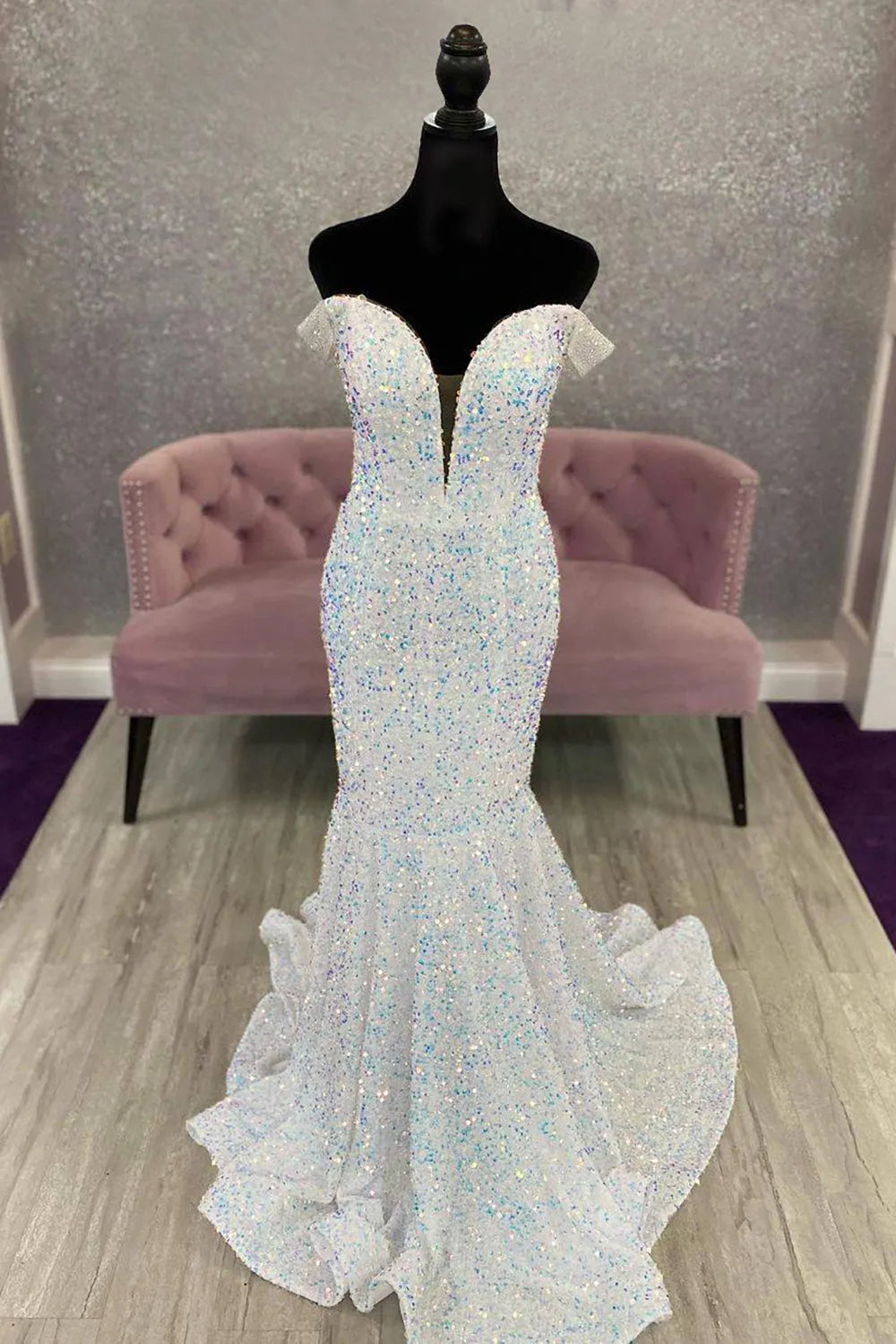 Woman wearing a dazzling off-shoulder sequin mermaid prom dress with an open back.