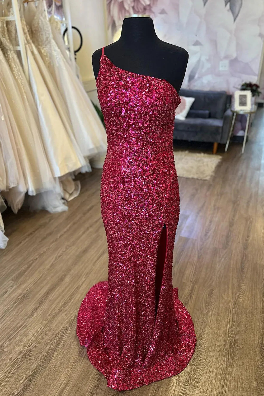 Model wearing a dazzling mermaid one-shoulder sequin long prom dress with a high split front.