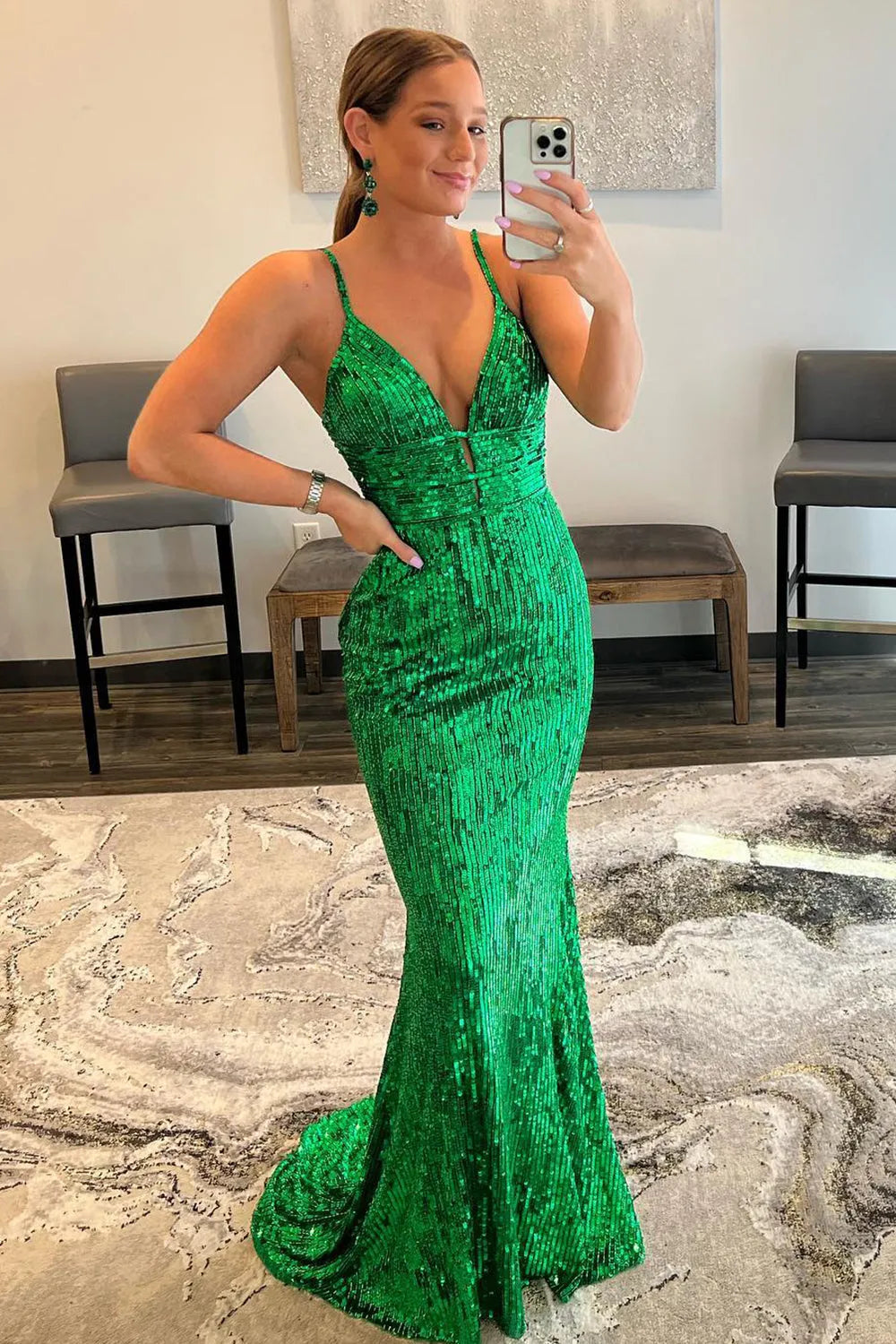 Woman wearing a silver sequin mermaid prom dress with spaghetti straps and a backless design.