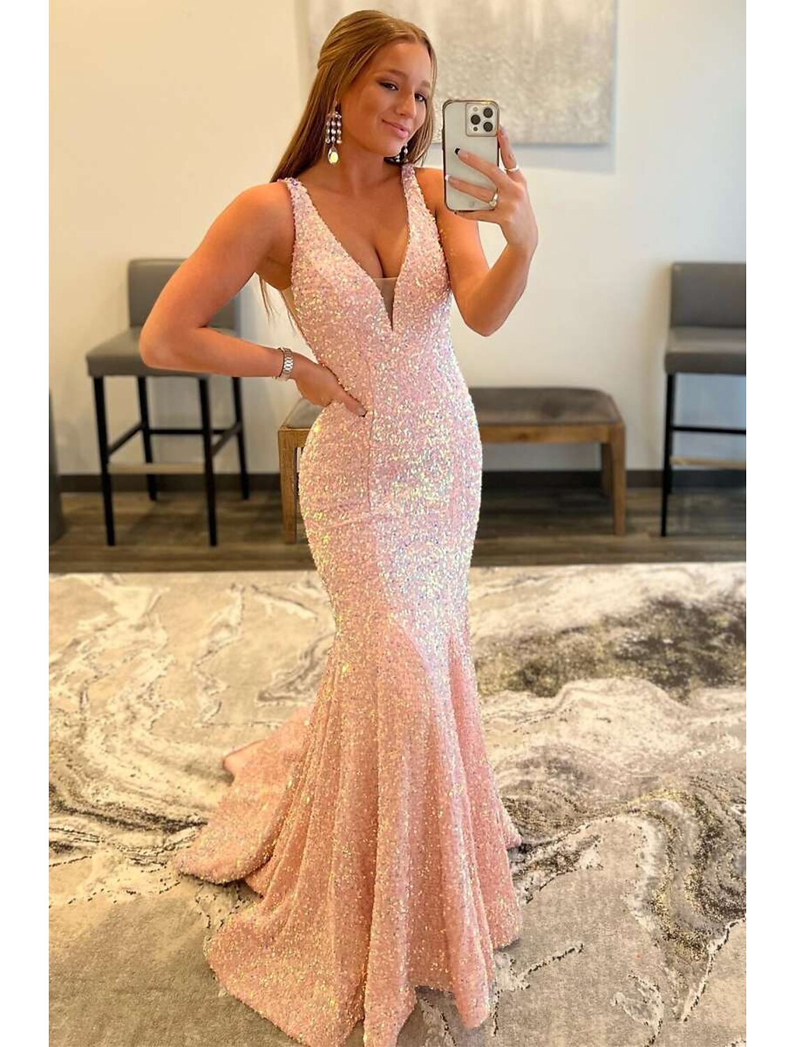 Woman posing in a dazzling sequined mermaid V-neck prom dress with a sweep train.