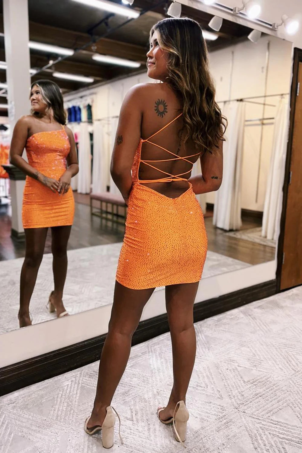 Back view of an orange sparkly one-shoulder beaded bodycon mini dress, showcasing the fitted silhouette.